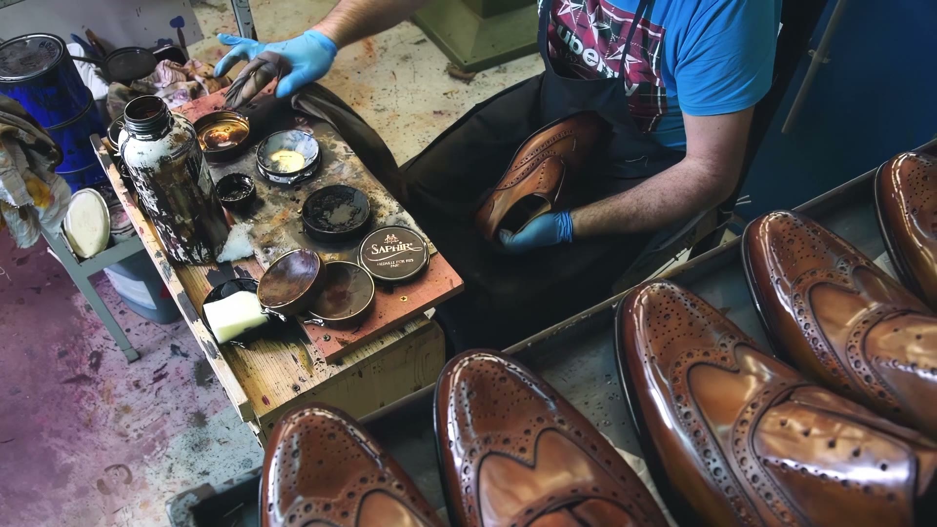 An artisan hand-polishing brown wingtips at a workbench in Naples