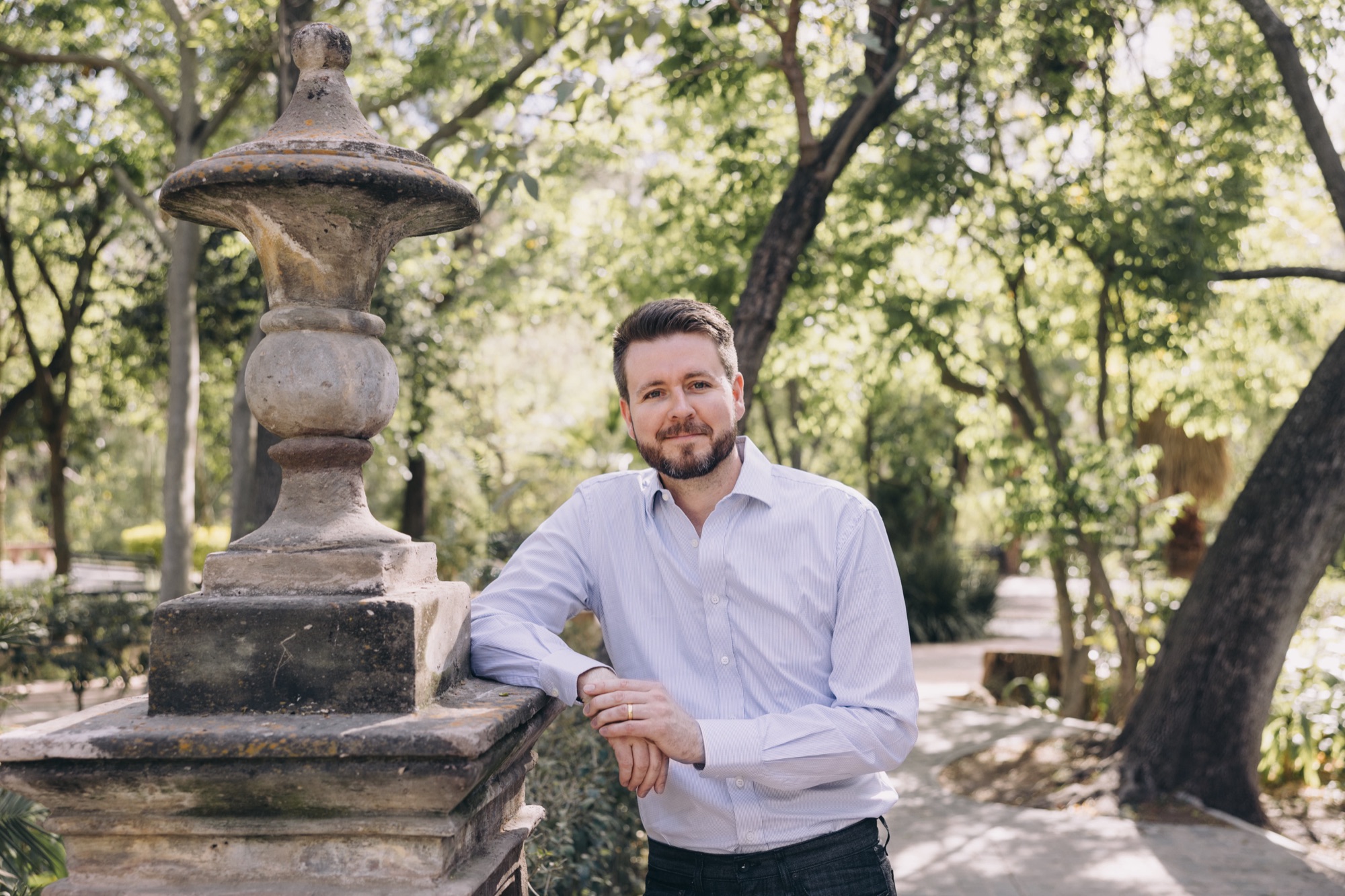 Benjamin Earley leaning on a stone pillar in a garden